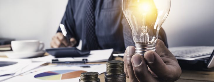 homem-de-negocios-segurando-uma-lampada-com-moedas-dinheiro-e-espaco-de-copia-para-contabilidade-ideias-e-conceito-criativo-